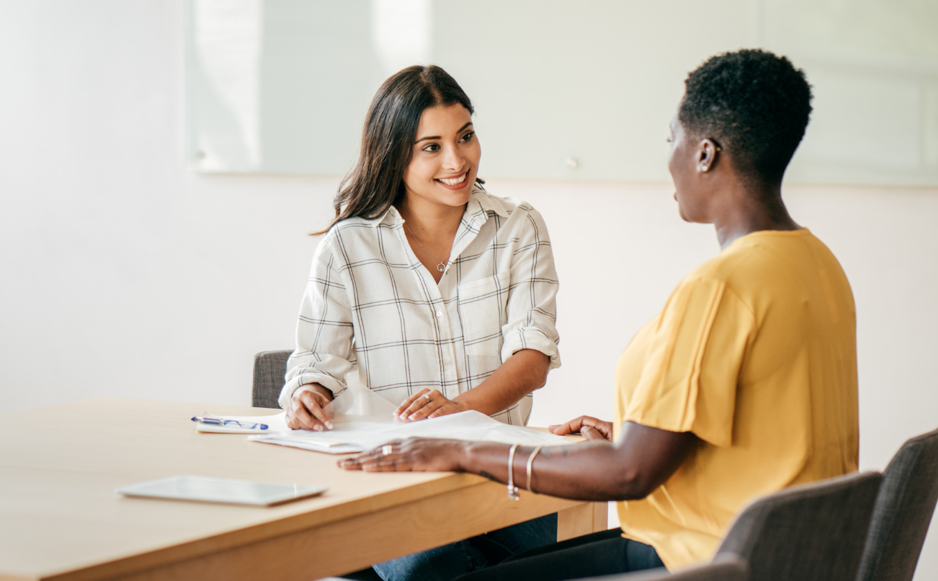 Two professionals reviewing documents during a hiring conversation